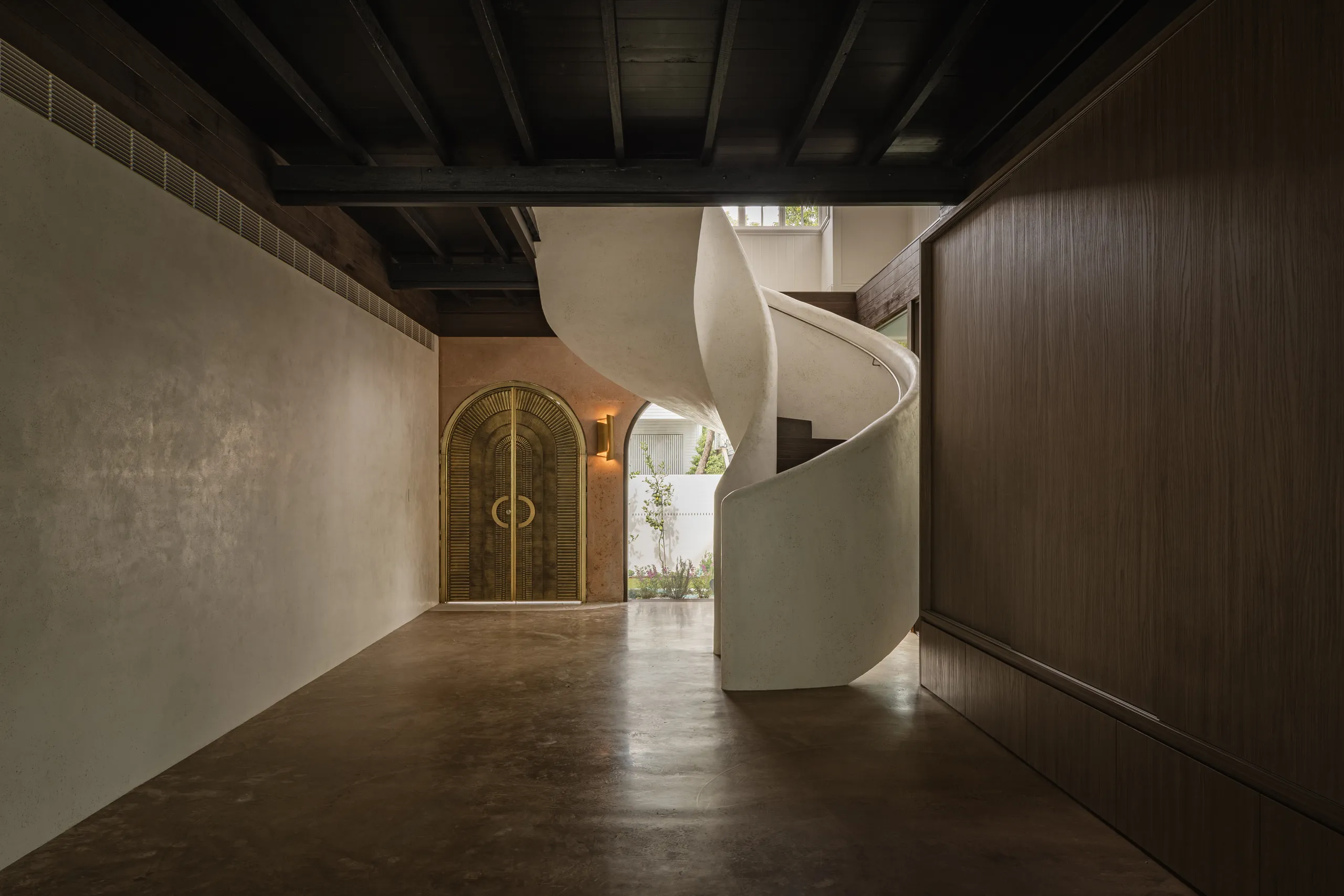 Sculptural white spiral staircase against dark timber joinery and brass doors — Mark St.